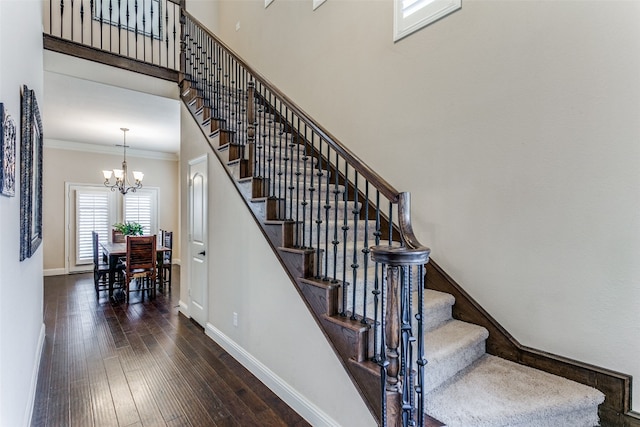 stairs featuring hardwood / wood-style flooring, crown molding, and a chandelier