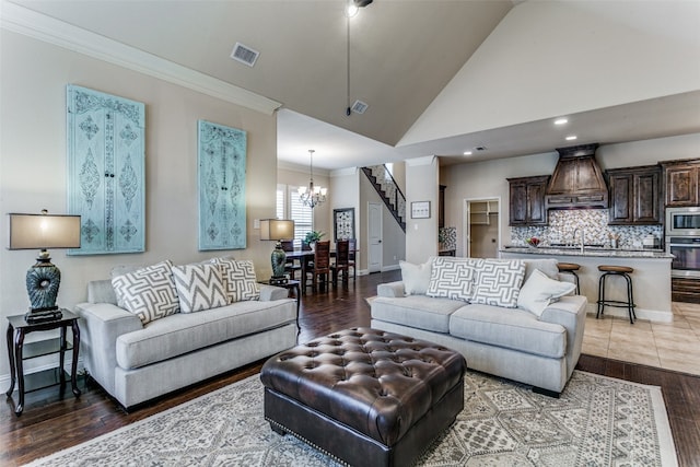 living room featuring high vaulted ceiling, crown molding, an inviting chandelier, hardwood / wood-style flooring, and sink