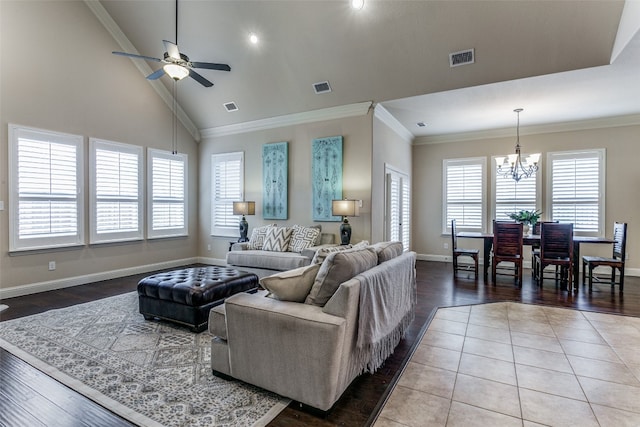 living room with ceiling fan with notable chandelier, ornamental molding, light hardwood / wood-style flooring, and high vaulted ceiling