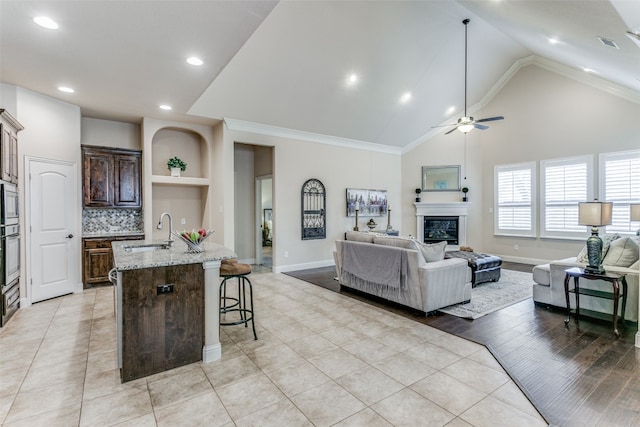 interior space featuring ceiling fan, lofted ceiling, ornamental molding, sink, and light hardwood / wood-style floors