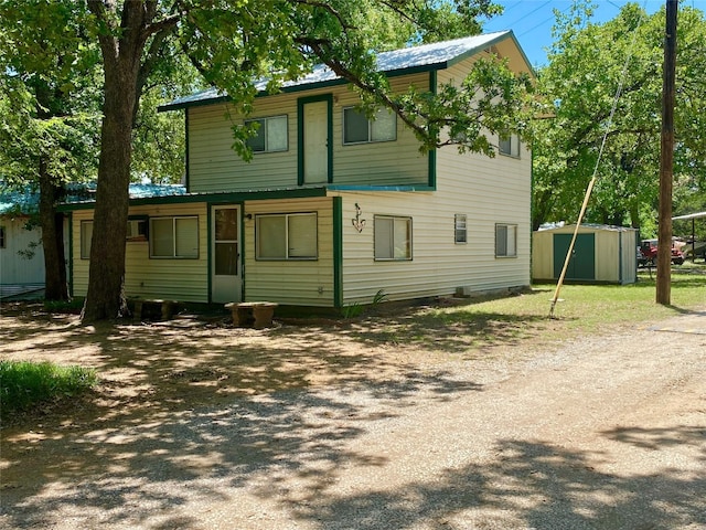 rear view of house with a storage shed and a yard