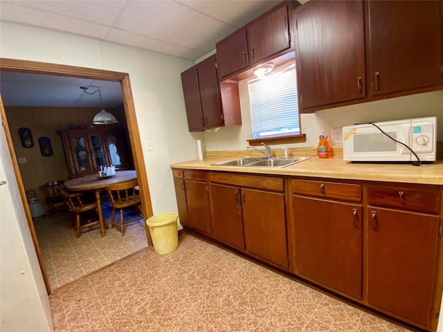 kitchen featuring a drop ceiling, light tile flooring, and sink