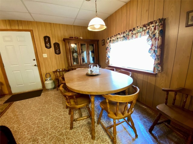 tiled dining space with wood walls and a drop ceiling