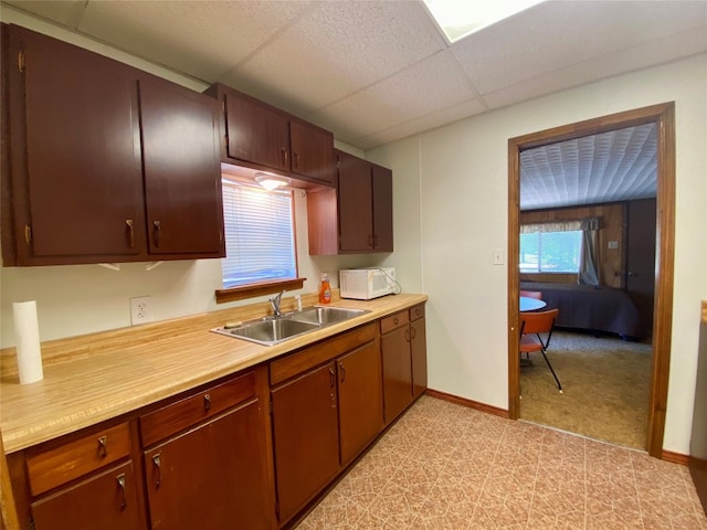 kitchen with a drop ceiling, sink, and light tile floors