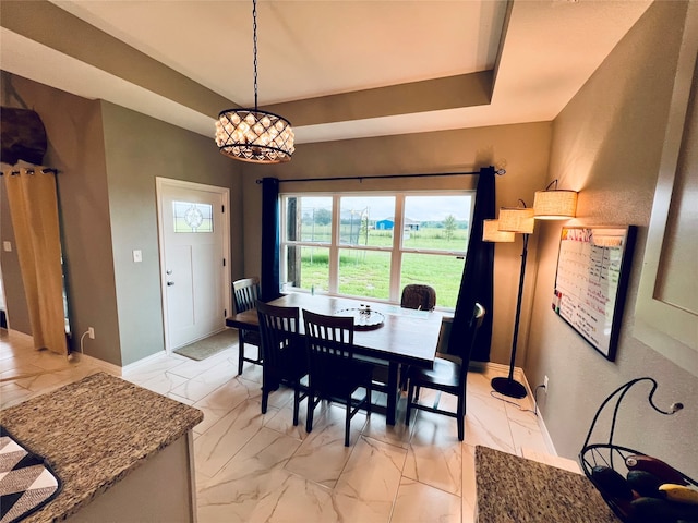 dining area featuring a raised ceiling and a chandelier