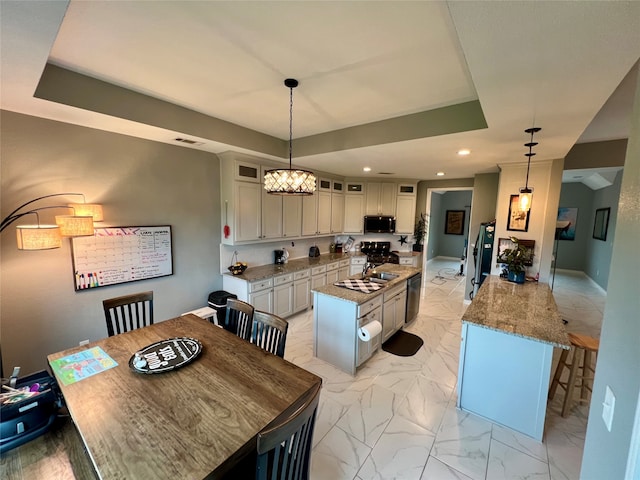 kitchen with hanging light fixtures, light stone countertops, white cabinets, a kitchen island, and a raised ceiling