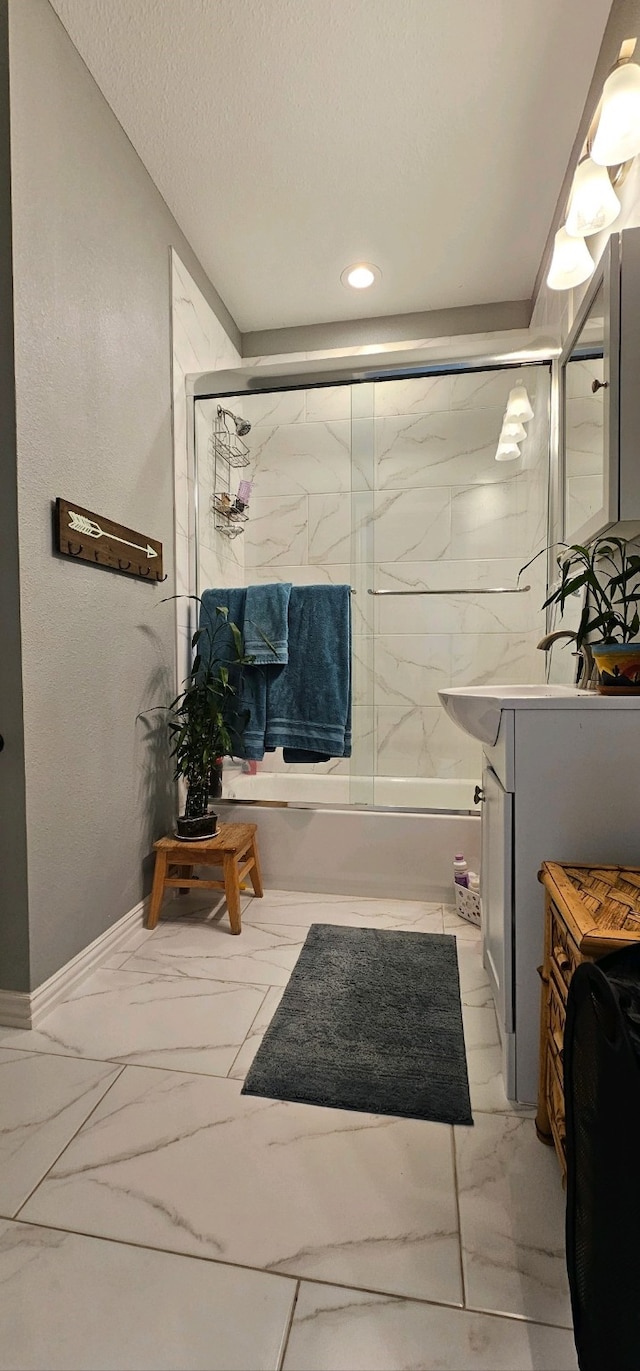 bathroom with enclosed tub / shower combo, vanity, and a textured ceiling