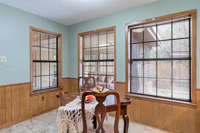 tiled dining room featuring a wealth of natural light and wooden walls