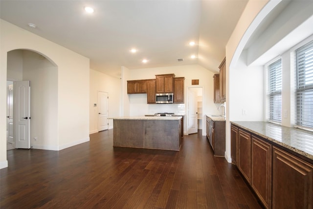 kitchen with light stone countertops, backsplash, sink, vaulted ceiling, and dark hardwood / wood-style flooring