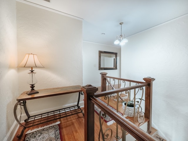 hall with crown molding, hardwood / wood-style floors, and an inviting chandelier