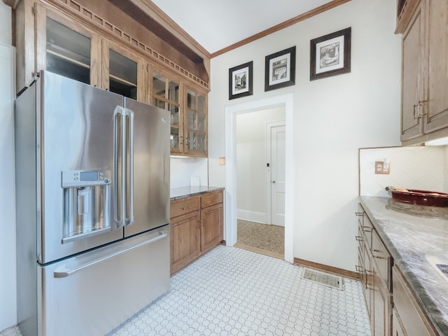 kitchen with tasteful backsplash, light stone counters, light tile floors, ornamental molding, and high end fridge