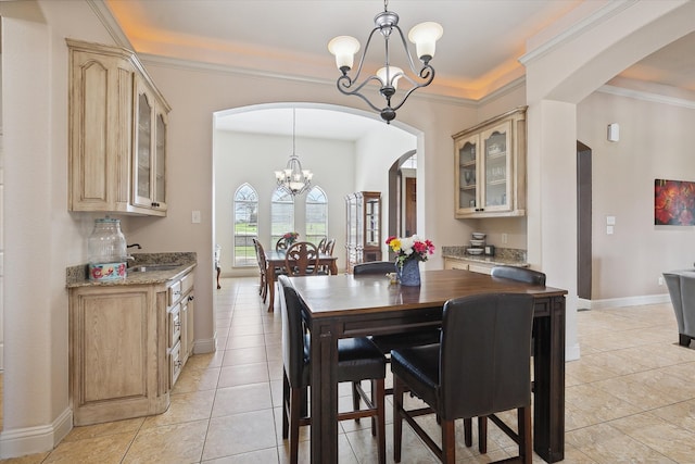 dining space with sink, light tile patterned floors, crown molding, and a chandelier