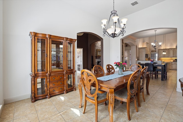 tiled dining room with lofted ceiling and an inviting chandelier