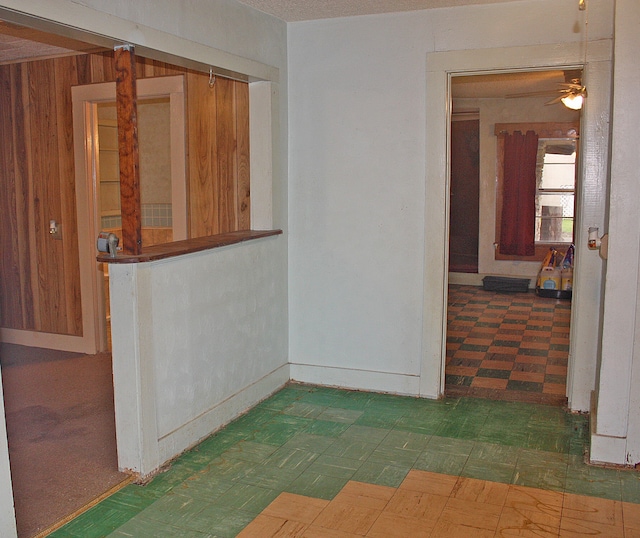 empty room featuring ceiling fan and wooden walls