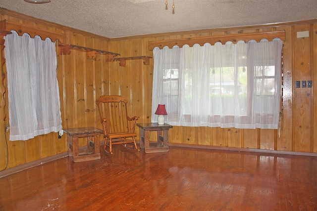 unfurnished room with hardwood / wood-style floors, a textured ceiling, and wood walls