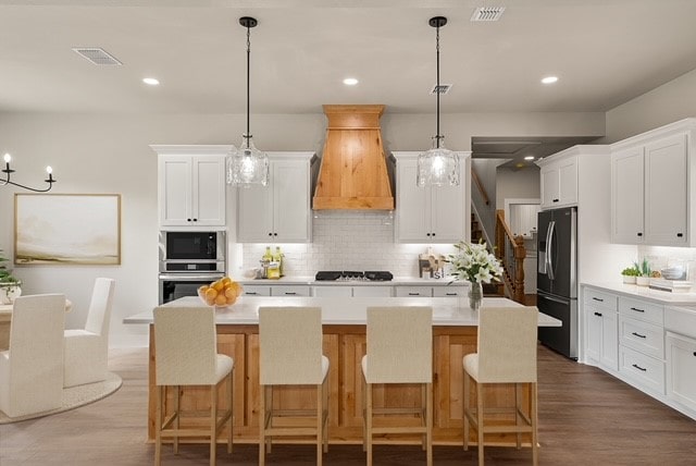 kitchen featuring black appliances, white cabinetry, custom exhaust hood, and decorative light fixtures