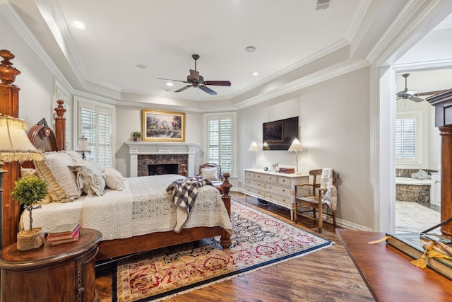 bedroom featuring a premium fireplace, hardwood / wood-style flooring, ornamental molding, and ceiling fan