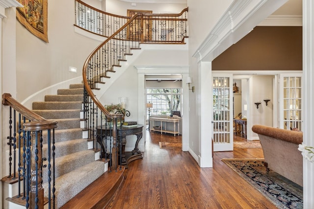 foyer entrance with a towering ceiling, crown molding, and hardwood / wood-style flooring