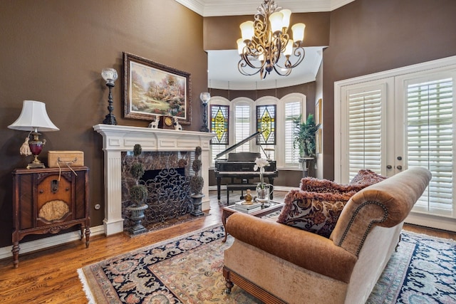 living room featuring crown molding, french doors, a high end fireplace, an inviting chandelier, and hardwood / wood-style flooring