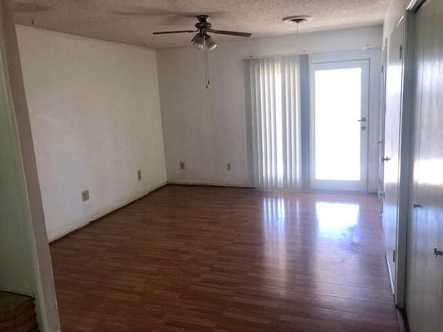 spare room featuring dark hardwood / wood-style flooring, ceiling fan, and a textured ceiling