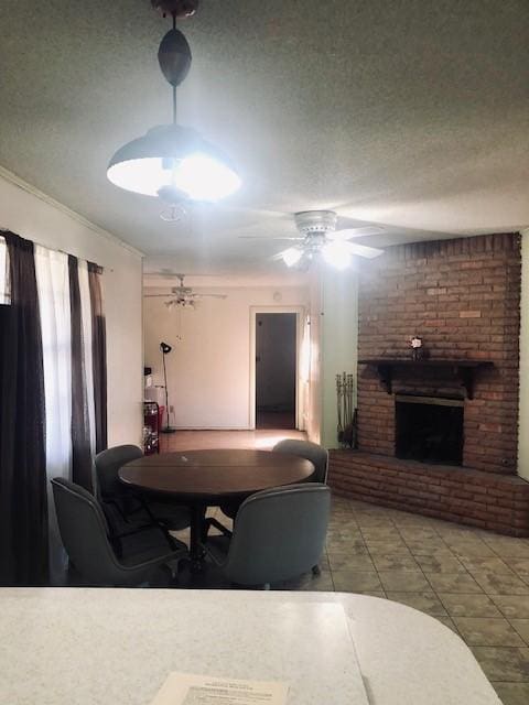 dining room featuring ceiling fan, light tile patterned floors, a fireplace, and a textured ceiling