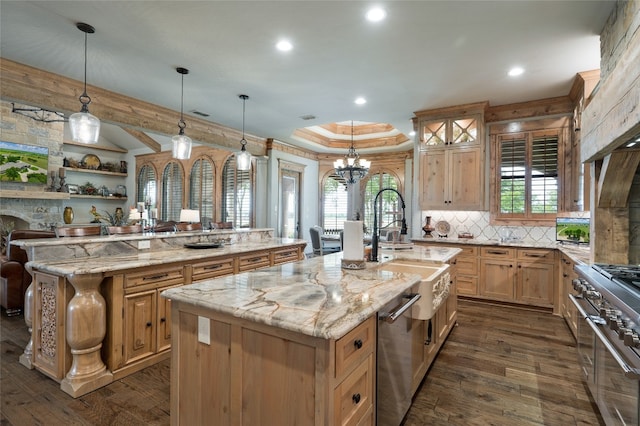 kitchen with a chandelier, dark hardwood / wood-style floors, an island with sink, light stone countertops, and hanging light fixtures