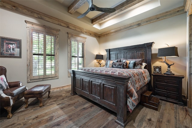 bedroom featuring ceiling fan, beamed ceiling, ornamental molding, dark wood-type flooring, and a tray ceiling