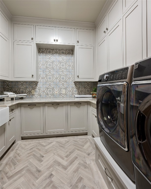 washroom featuring light parquet floors, crown molding, cabinets, and washer and clothes dryer