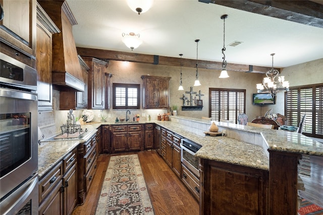 kitchen with an inviting chandelier, dark wood-type flooring, hanging light fixtures, and a healthy amount of sunlight