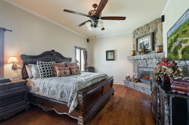 bedroom featuring ornamental molding, a stone fireplace, ceiling fan, and dark hardwood / wood-style flooring