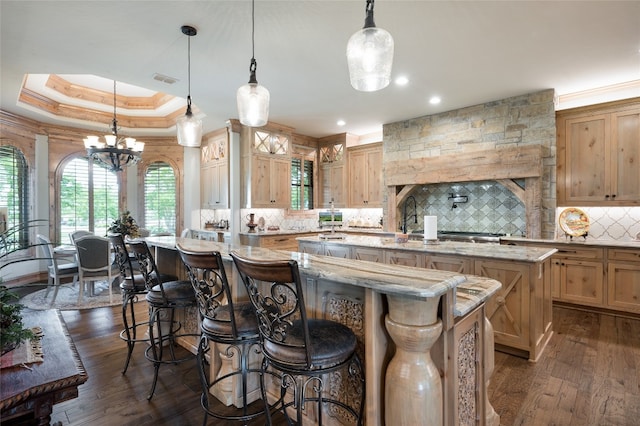 kitchen with plenty of natural light, a kitchen island with sink, dark hardwood / wood-style floors, and an inviting chandelier