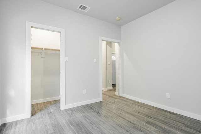 unfurnished bedroom with a walk in closet, light wood-type flooring, and a closet