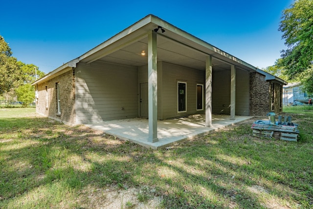 rear view of property featuring a lawn and a patio