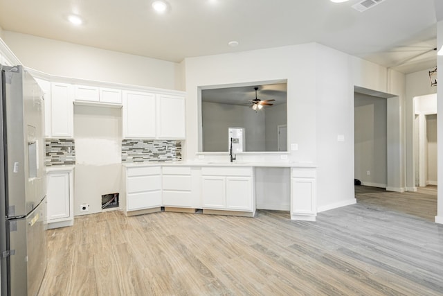 kitchen with stainless steel refrigerator with ice dispenser, white cabinets, ceiling fan, light wood-type flooring, and tasteful backsplash