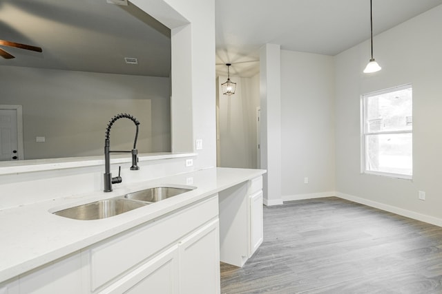 kitchen with sink, light hardwood / wood-style flooring, ceiling fan, and hanging light fixtures