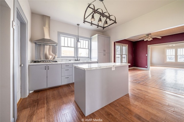 1832 Commercial Ave, Anson, TX 79501 - kitchen with hardwood / wood-style flooring, range hood, a center island, stainless steel gas cooktop, and decorative light fixtures