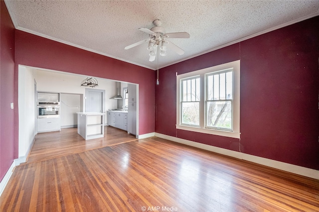 1832 Commercial Ave, Anson, TX 79501 - unfurnished living room with crown molding, hardwood / wood-style flooring, a textured ceiling, and ceiling fan
