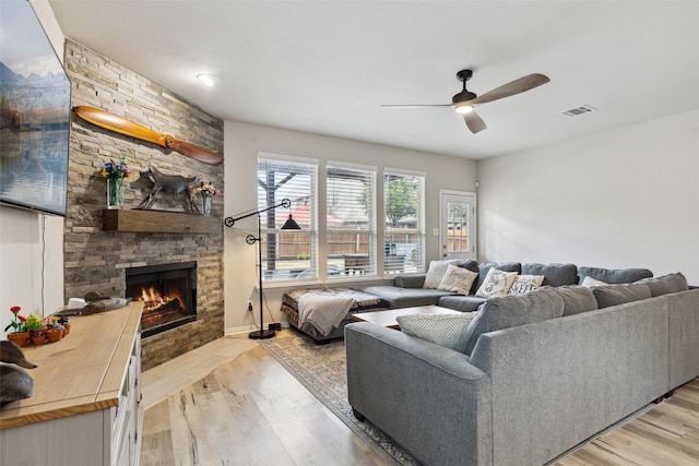 living room with a fireplace, ceiling fan, and light hardwood / wood-style flooring