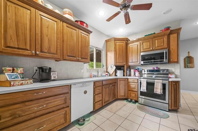 kitchen with backsplash, sink, light tile patterned floors, and stainless steel appliances