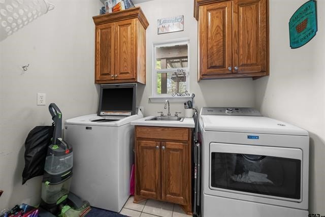 laundry room with cabinets, light tile patterned floors, washing machine and dryer, and sink