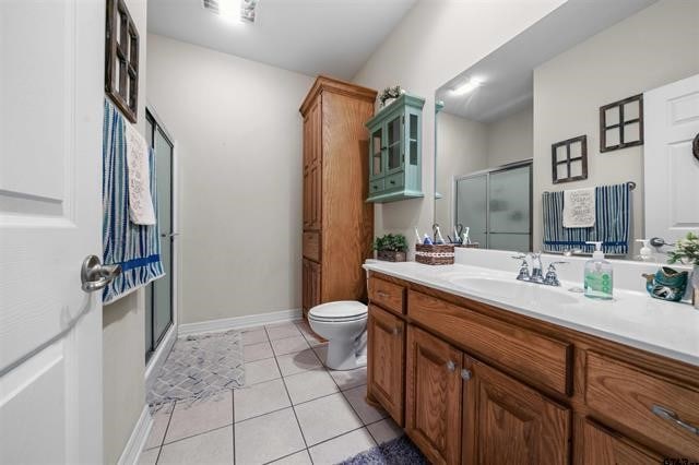 bathroom featuring tile patterned flooring, vanity, toilet, and walk in shower