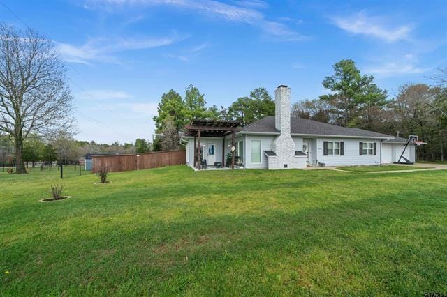 back of house featuring a pergola and a lawn