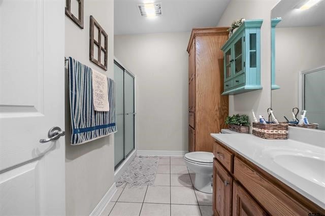 bathroom with toilet, vanity, tile patterned floors, and an enclosed shower