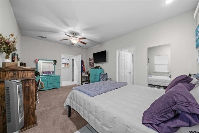 bedroom featuring light carpet, ensuite bath, and ceiling fan