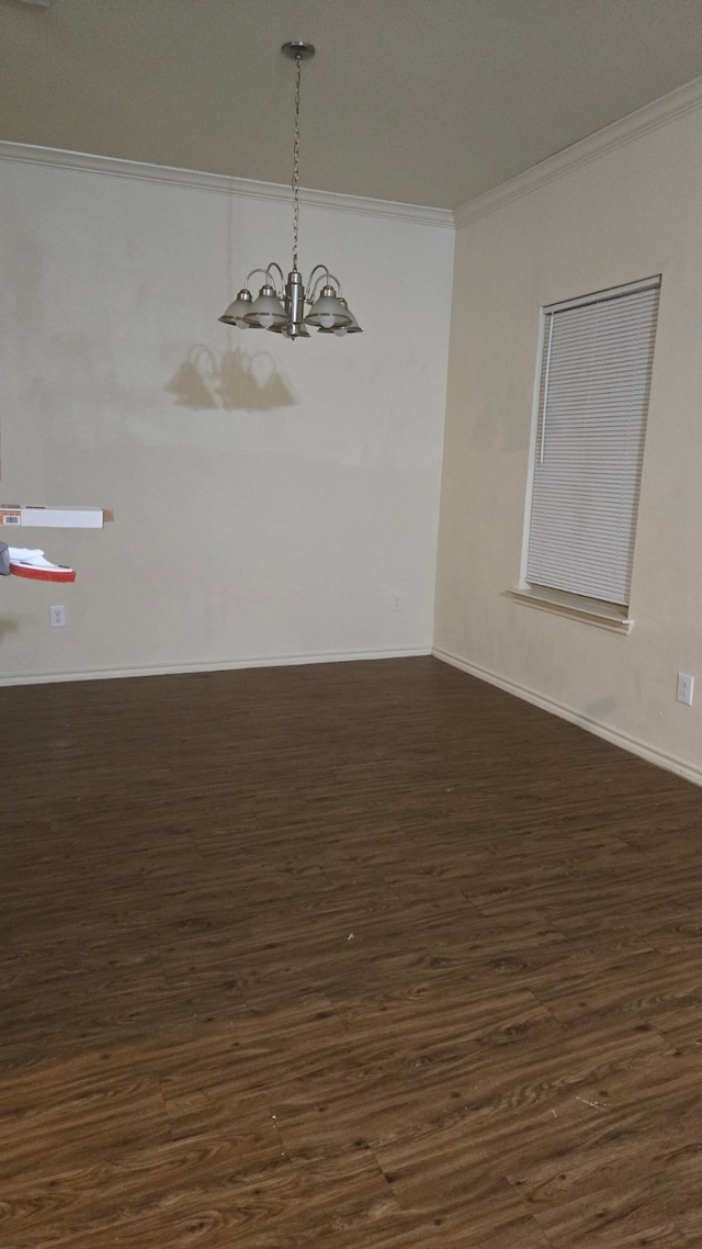 empty room featuring crown molding, dark wood-type flooring, and an inviting chandelier