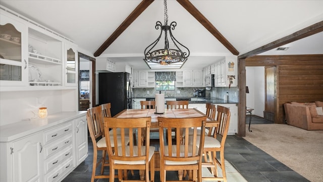 carpeted dining space with lofted ceiling with beams, sink, and a chandelier