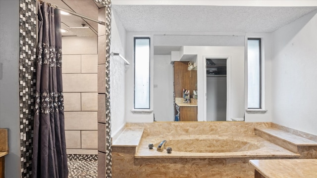 bathroom featuring a textured ceiling, vanity, and a relaxing tiled bath