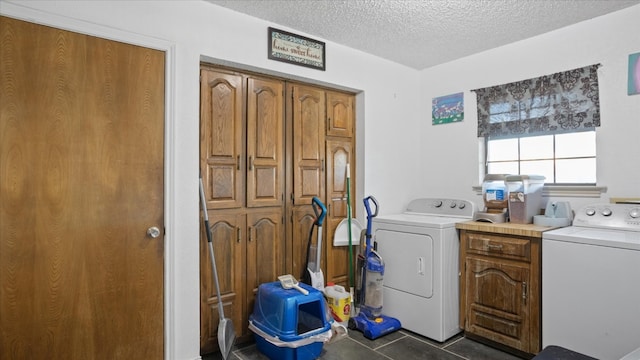 washroom featuring cabinets, a textured ceiling, dark tile flooring, and washer and dryer