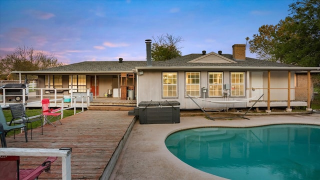 back house at dusk with a swimming pool side deck