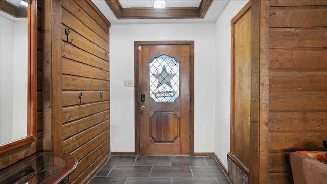 doorway featuring dark tile flooring and a tray ceiling